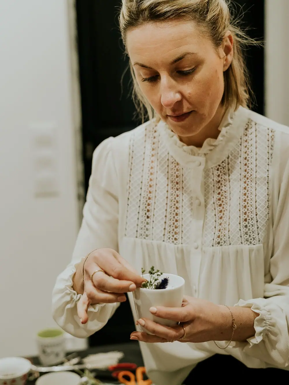 Margo déposant des fleurs séchées sur une création parfumée