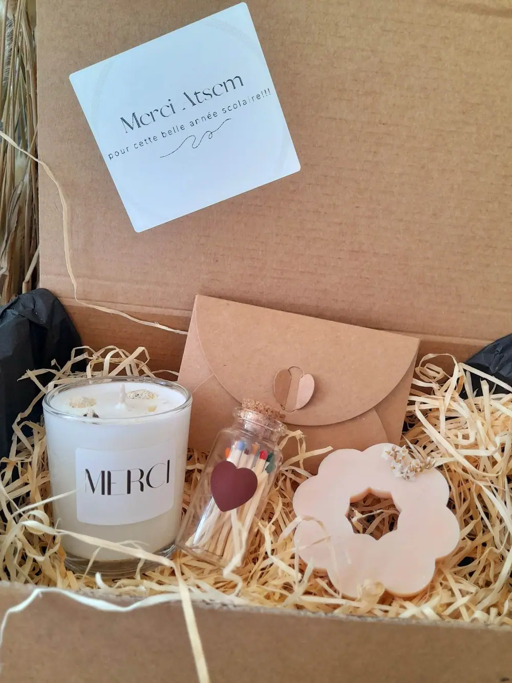 Coffret cadeau ouvert avec bougie et fondants sur frisure de bois