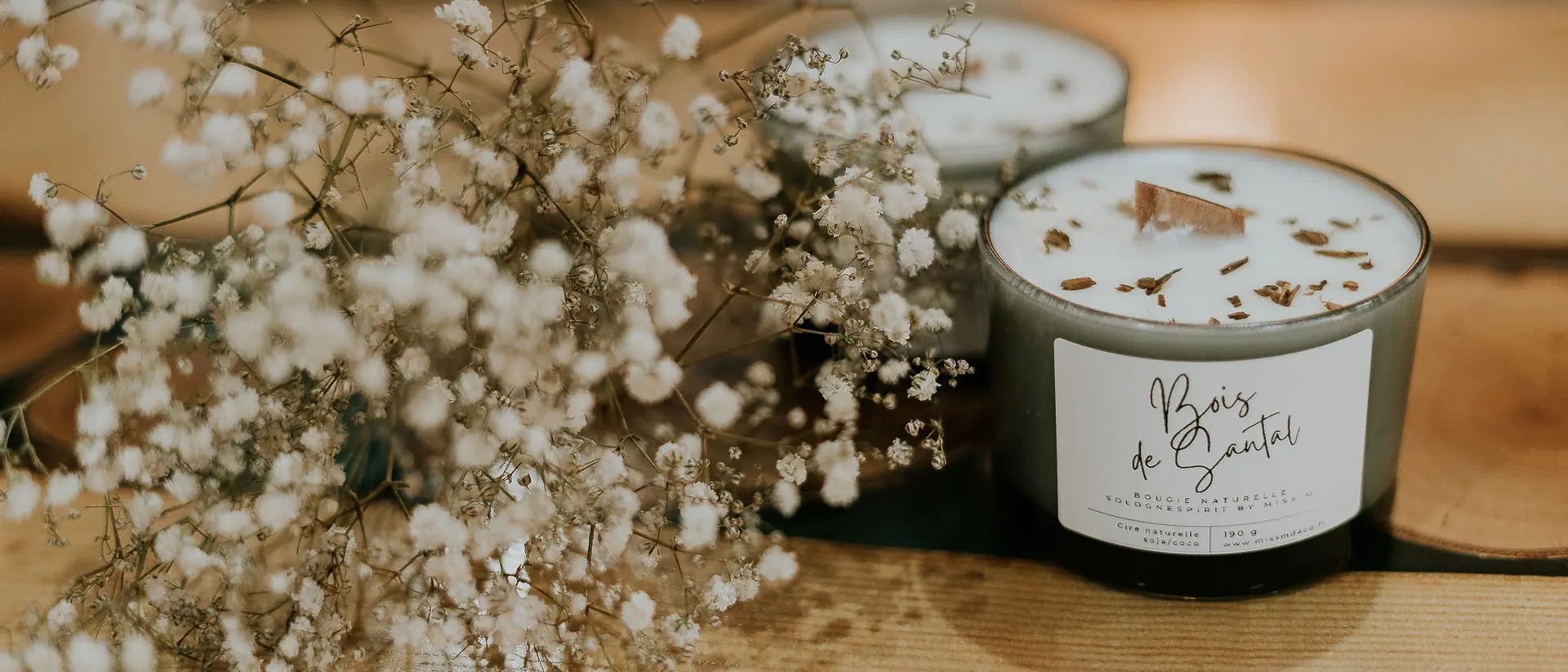 Bougies parfumées et fleurs séchées disposées sur une table de l’atelier