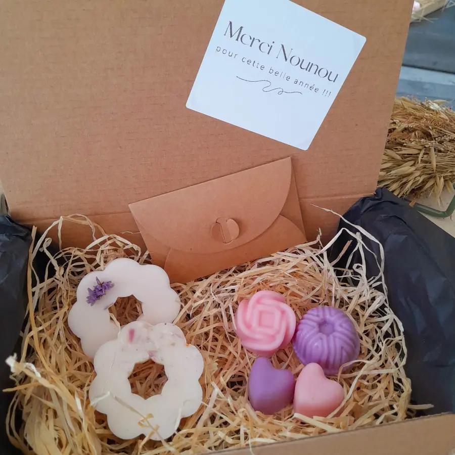 Coffret cadeau ouvert révélant une bougie et des fondants sur frisure de bois