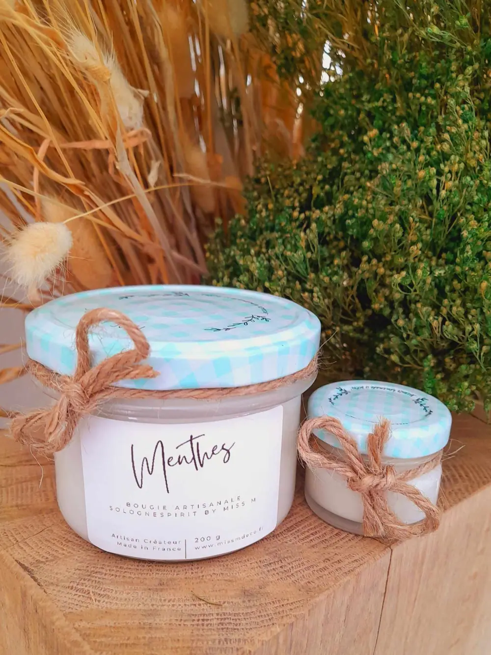 Bougie parfumée artisanale posée parmi des herbes séchées de Sologne