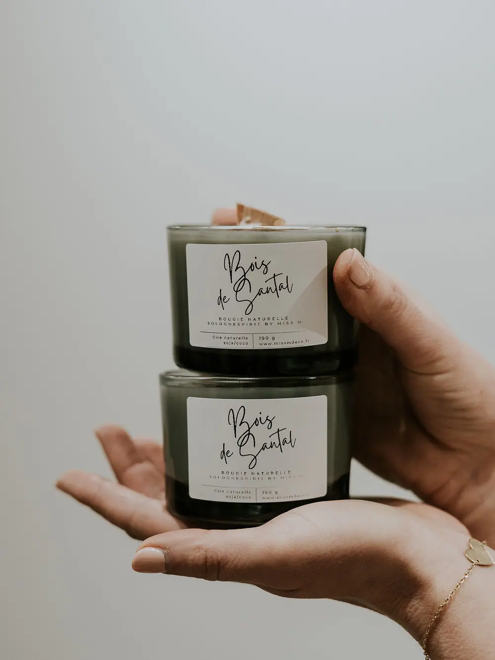 Deux bougies Bois de santal en verre fumé tenues à la main
